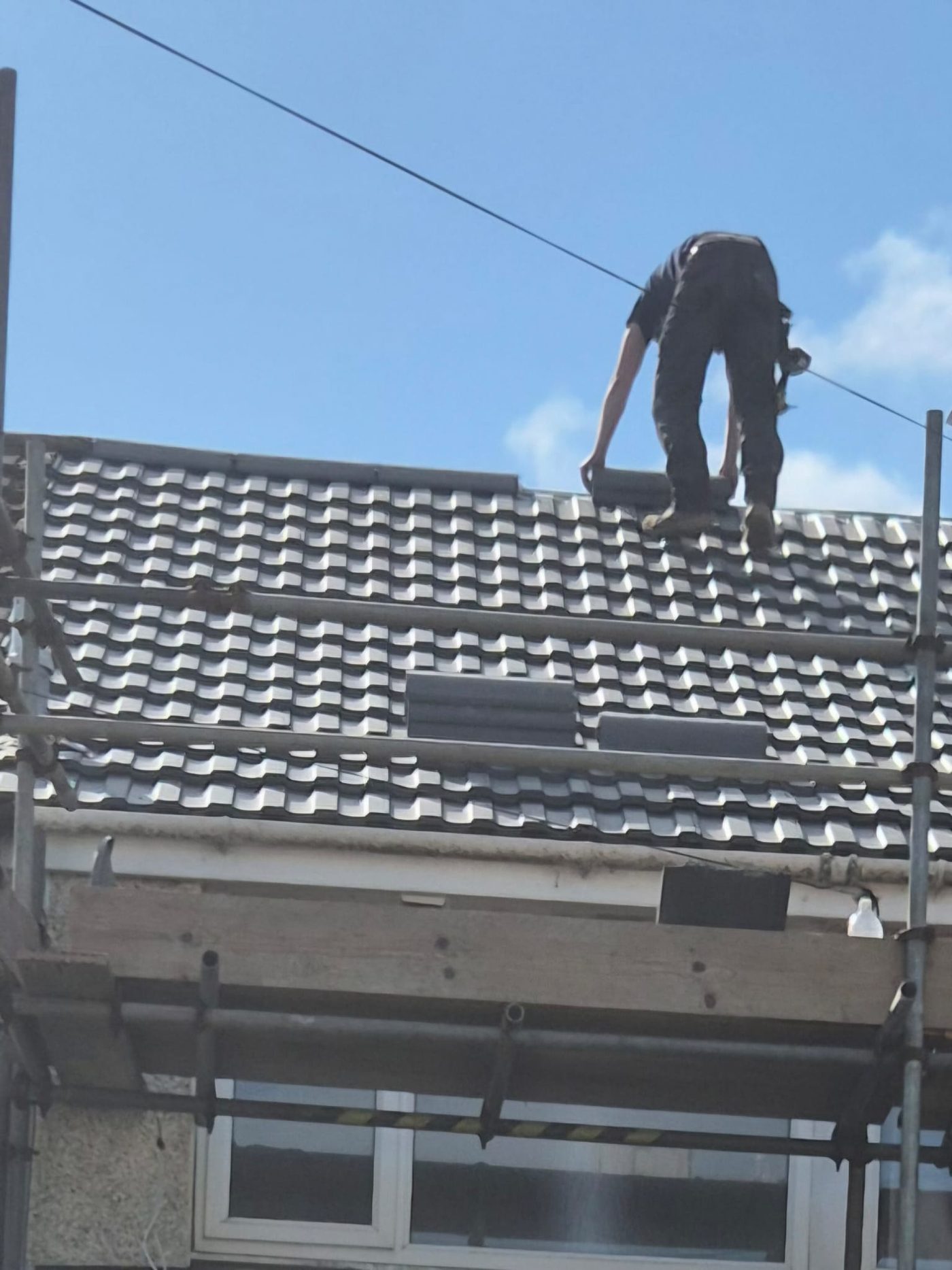 Roofer on a finished black tile roof