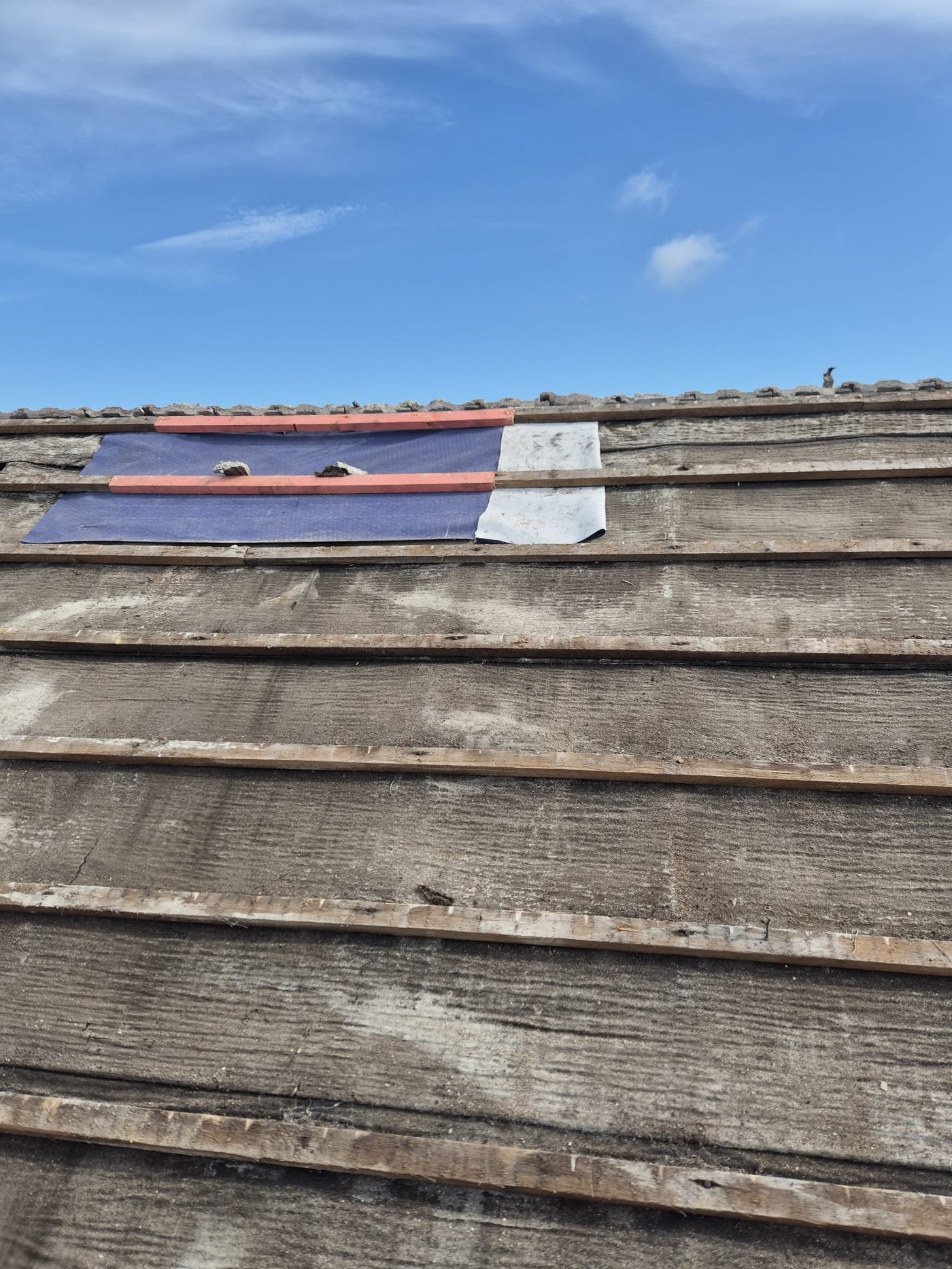 Fresh battens against blue sky on a stripped pitched roof